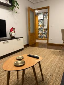 Una sala de estar con una mesa con un control remoto encima. en El Pasaje Apartamento, en Oviedo