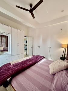 a bedroom with a large bed with a ceiling fan at The Little Idyll in Dharmsala