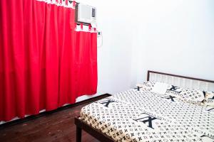 Del CarmenMangrove Breeze Country Inn by RedDoorz的一间卧室配有一张带红色窗帘的床