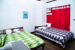 Del CarmenMangrove Breeze Country Inn by RedDoorz的有两张床和红色窗帘的房间