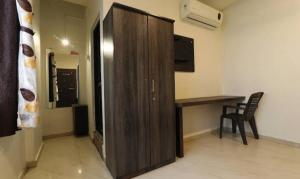 ein großer Holzschrank in einem Raum mit einem Schreibtisch in der Unterkunft Suman Lodging near Mahalaxmi Temple, Kolhapur in Kolhapur