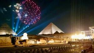 a fireworks show in front of the pyramids at night at Anubis kingdom pyramids view in Cairo