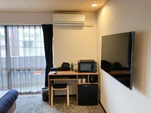 那霸ホテルリブマックス那覇波の上2的客房设有书桌、微波炉和电视。