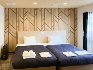 那霸ホテルリブマックス那覇波の上2的一间卧室，有两张床，床上有毛巾