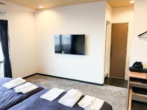 那霸ホテルリブマックス那覇波の上2的一间卧室，有两张床和一台挂在墙上的电视