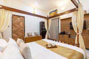 a bedroom with a large bed and a television at SaffronStays Shreevats in Bedla
