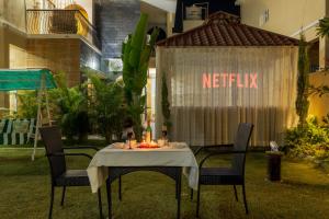 a table with two chairs and a netflix sign on it at SaffronStays Shreevats in Bedla