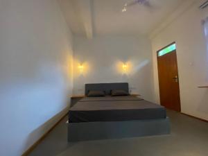 Un dormitorio con una cama en una habitación blanca. en Bird garden Midigama, en Kumbalgama 12 fotos más