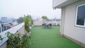 ein Balkon mit grünem Gras und einem Tisch und Stühlen in der Unterkunft Central suites with Terrace by Luxury Heights in Gurgaon
