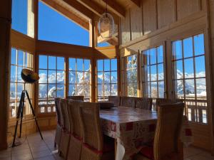 a dining room with a table and chairs and windows at Chalet Rosablanche in Veysonnaz