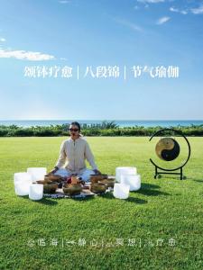 a man sitting on the grass with a table of food at Yalong Bay Mangrove Tree Resort in Sanya