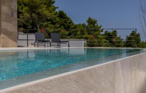 a swimming pool with two chairs sitting next to it at Luxurious Home In Dingac With Sauna in Gornji Dingač