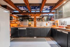 eine große Küche mit schwarzen Schränken und Holzdecken in der Unterkunft La Maison des Colombages - Proche Strasbourg in Schiltigheim