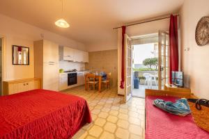 a bedroom with a red bed and a kitchen at Green Marine in Silvi Marina