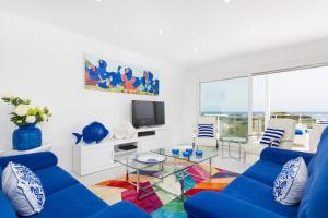 a living room with a blue couch and a glass table at Villa Paradise by Escape Home in Son Bou
