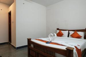 a bedroom with a bed with orange and white pillows at UNIQUE RESORT Inn Yercaud in Yercaud