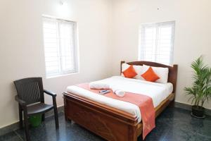 a bedroom with a bed and a chair and windows at UNIQUE RESORT Inn Yercaud in Yercaud