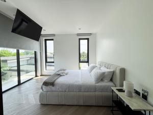a white bedroom with a large bed and a flat screen tv at Luxe & Privacy Orchard Villas Pasak 4BR in Laguna Phuket +19 photos