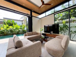 a living room with two chairs and a flat screen tv at Luxe & Privacy Orchard Villas Pasak 4BR in Laguna Phuket