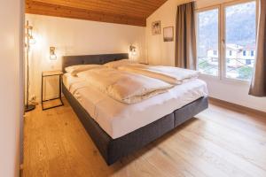 uma cama grande num quarto com uma janela grande em Surfers Lodge near Interlaken, at lake with pool em Därligen