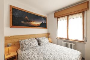 a bedroom with a bed and two windows at Dolomitihouse FRASSEN in Fiera di Primiero +46 photos