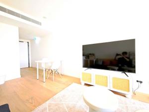 Box Hill Bright and Cozy Hotel Style One Bedroom Suite Kitchenette Ideal for Short Stays في بوكسهل: غرفة معيشة بيضاء مع طاولة وتلفزيون