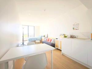 Box Hill Bright and Cozy Hotel Style One Bedroom Suite Kitchenette Ideal for Short Stays في بوكسهل: مطبخ وغرفة معيشة مع طاولة وكراسي بيضاء