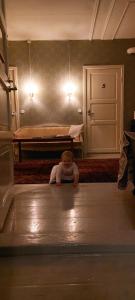 a baby sitting on the floor in a room at Hostel Cafe Huvila in Oulu