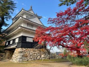 um templo com uma árvore vermelha em frente a ele em 豊橋民泊 最大13名様 駐車場2台無料 駅徒歩7分 Traditional Japanese house ,Toyohashi Aichi ,7 minutes walk from the station ,2 free parking em Toyohashi