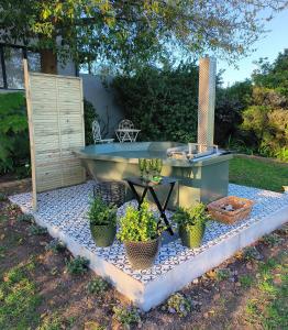 Una bañera al aire libre con plantas en macetas sobre una losa de guijarros. en Gilgal Guest Accommodation, en Onder-Papegaaiberg
