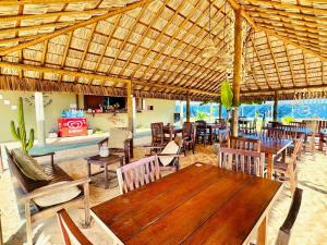 a restaurant with a wooden table and chairs at Amigos do Vento Chalés e Kite Point in Touros