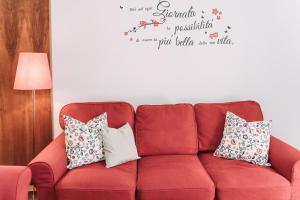 Palladio Apartment - In Centro con Garage, Vista Fiume, Jacuzzi في فيتشنزا: أريكة حمراء مع وسائد في غرفة المعيشة