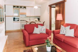 Palladio Apartment - In Centro con Garage, Vista Fiume, Jacuzzi في فيتشنزا: غرفة معيشة مع كرسيين حمر ومطبخ +37 صورة