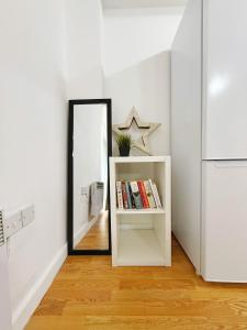 a mirror in a white room with a shelf with books at City Center Balcony by the Universities in Manchester +14 photos