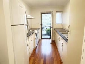 a kitchen with white appliances and a wooden floor at Cosy Ground Floor Walk to Adelaide Oval, City, Zoo & More in Adelaide