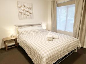 a bedroom with a bed with a checkered blanket and a window at Cosy Ground Floor Walk to Adelaide Oval, City, Zoo & More in Adelaide