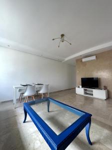een woonkamer met een blauwe tafel en een tv bij La Perle Aïn Diab Beachfront in Casablanca