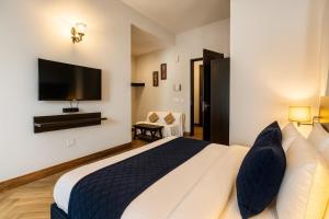 a bedroom with a large bed and a flat screen tv at Pearl Grand Boutique Cottage In Omaxe Anandam Vrindavan -# Premium AC Rooms With Balcony # Big Parking # Lift # Garden # Peaceful Area # Near Prem Mandir # Property Of The Year # Most Awarded in Vrindāvan +27 photos