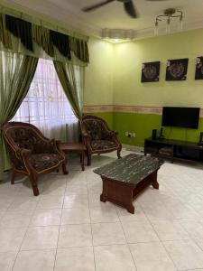 Una sala de estar con sillas, una mesa y un televisor. en Perdana Homestay Skudai, en Skudai