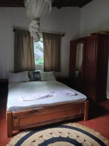 a bed in a bedroom with a window and a rug at Villa des îles Nosy Komba in Nosy Komba