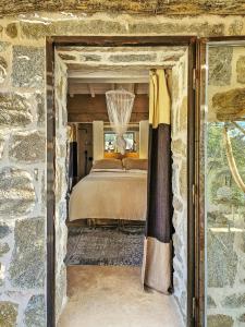 una camera da letto con un letto in un muro di pietra di Sea View House Among Holm Oaks On Elba a Seccheto Altre 30 foto
