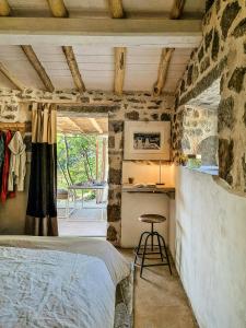 una camera da letto con un muro in pietra, un letto e un tavolo di Sea View House Among Holm Oaks On Elba a Seccheto