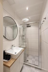 a white bathroom with a sink and a shower at Apartments Lia in Ljubljana