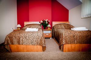 two beds in a hotel room with red walls at Hotel Słoneczne Tarasy in Grybów