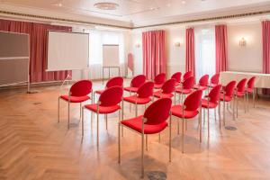 a conference room with red chairs and a whiteboard at Hotel Schwarzer Adler Tangermünde in Tangermünde