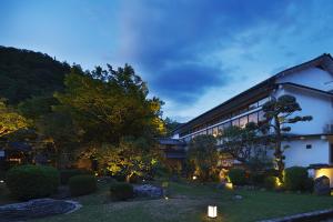 a building with a garden in front of it at Tokiwa Bekkan in Toyooka