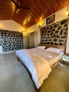 duże łóżko w sypialni z kamienną ścianą w obiekcie Nirvana Bhimashankar Jungle Resort w mieście Bhimashankar +27 zdjęć