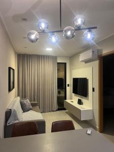 a living room with a couch and a table and a television at Studio Design 3 Lions in Maceió