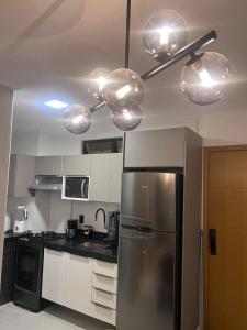 a kitchen with a stainless steel refrigerator and lights at Studio Design 3 Lions in Maceió