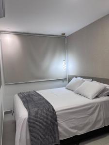 a bedroom with a white bed with a silver headboard at Studio Design 3 Lions in Maceió +13 photos